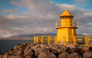 A yellow lighthouse on a rocky hill.
