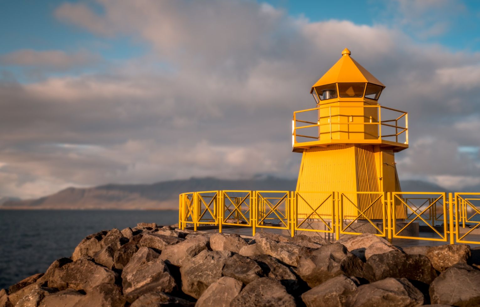 A yellow lighthouse on a rocky hill.